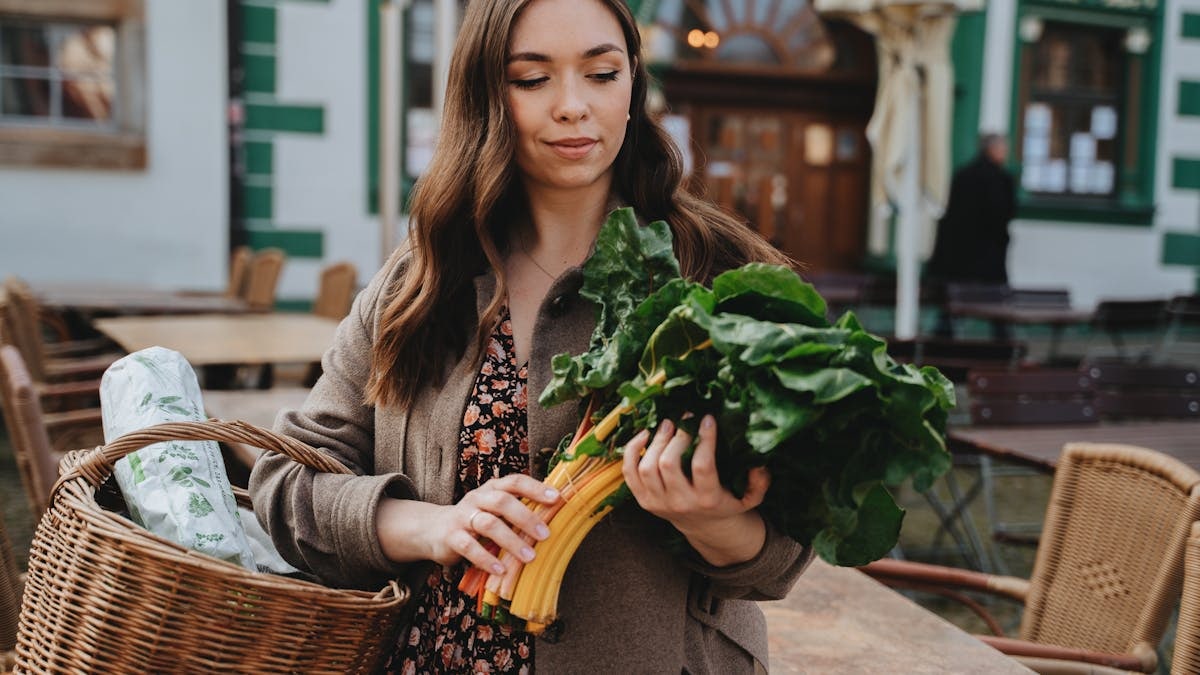 Young woman with a basket shopping for fresh vegetables outdoors in Erfurt, Germany.
